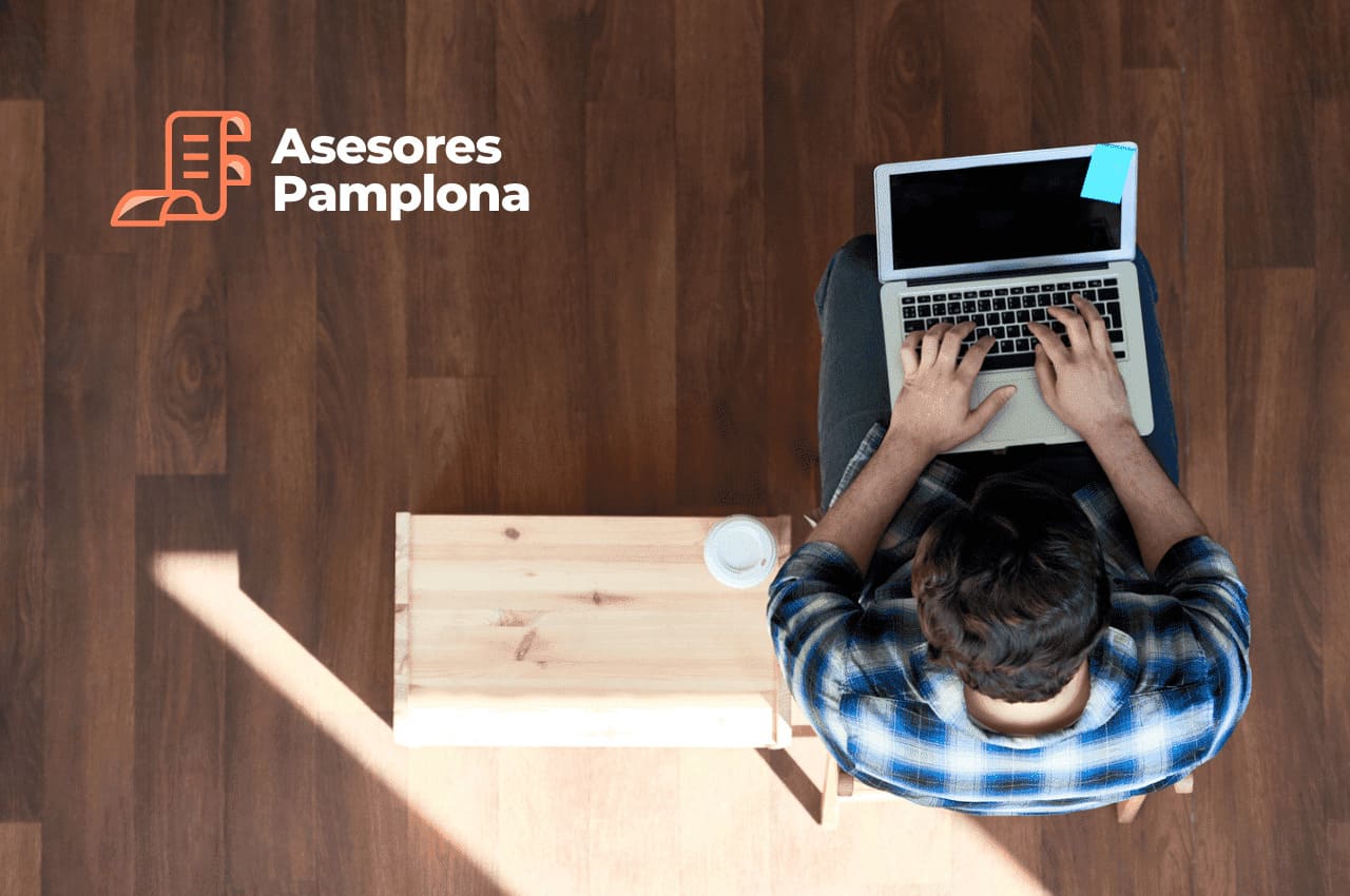 Imagen para artículo de blog con un autónomo trabajando en su ordenador portatil con un café al lado. La imagen es cenital.
